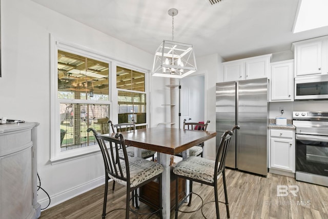 dining area featuring visible vents, an inviting chandelier, baseboards, and light wood-style floors