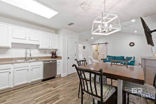 kitchen with visible vents, dishwasher, a barn door, and a sink