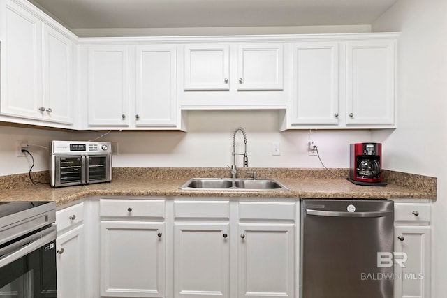 kitchen with a sink, appliances with stainless steel finishes, white cabinets, and light countertops