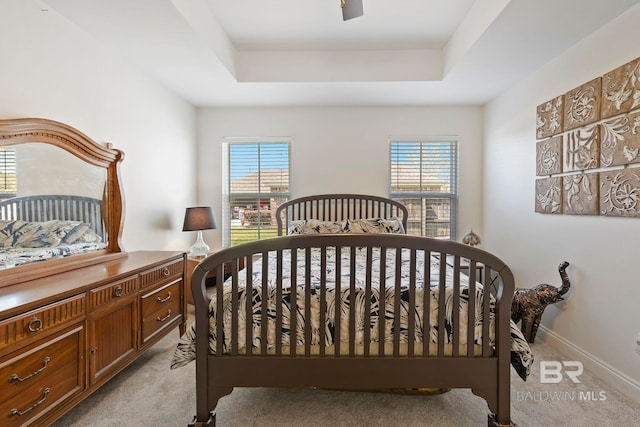 bedroom featuring light carpet, multiple windows, and a raised ceiling