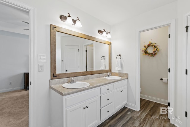 full bathroom featuring a sink, baseboards, and double vanity