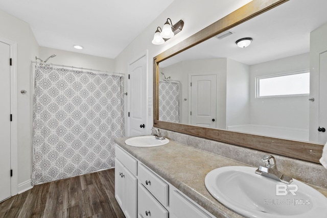 bathroom featuring double vanity, wood finished floors, visible vents, and a sink