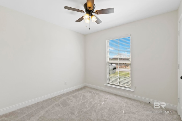 spare room featuring light colored carpet, a ceiling fan, and baseboards