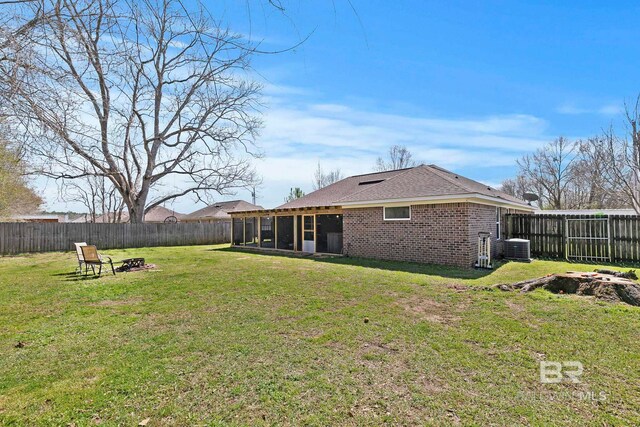 back of house featuring a yard, a fenced backyard, brick siding, and a sunroom