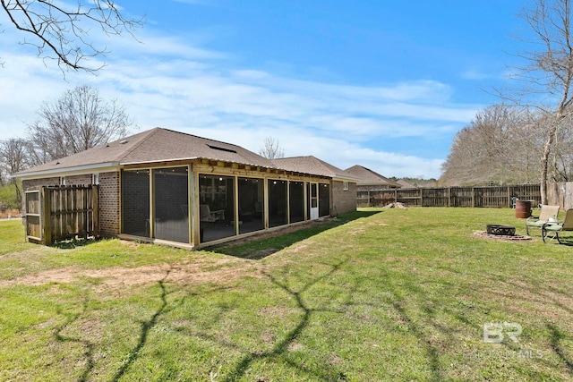 view of yard featuring a fire pit, a fenced backyard, and a sunroom