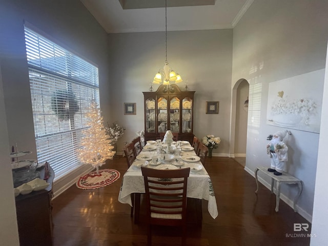 dining room featuring dark hardwood / wood-style flooring, ornamental molding, a towering ceiling, and a chandelier