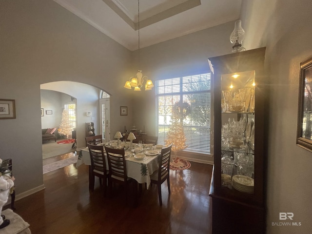 dining space featuring dark hardwood / wood-style flooring, ornamental molding, and an inviting chandelier