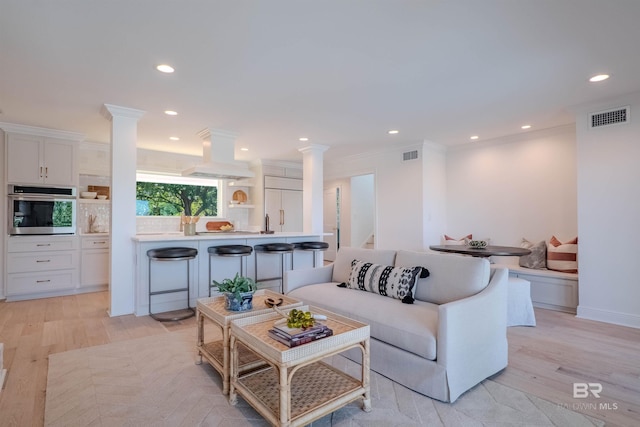 living room with breakfast area, light hardwood / wood-style floors, and crown molding