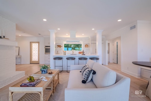 living room with light hardwood / wood-style floors, crown molding, and sink