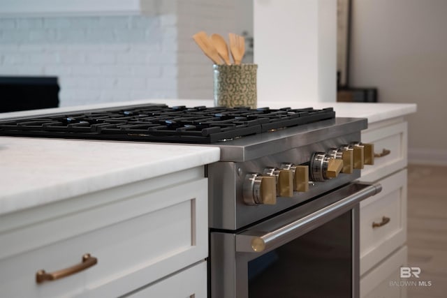 room details with white cabinets, decorative backsplash, and stainless steel stove