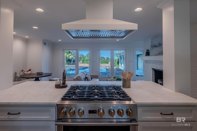 kitchen with range, island exhaust hood, and a brick fireplace