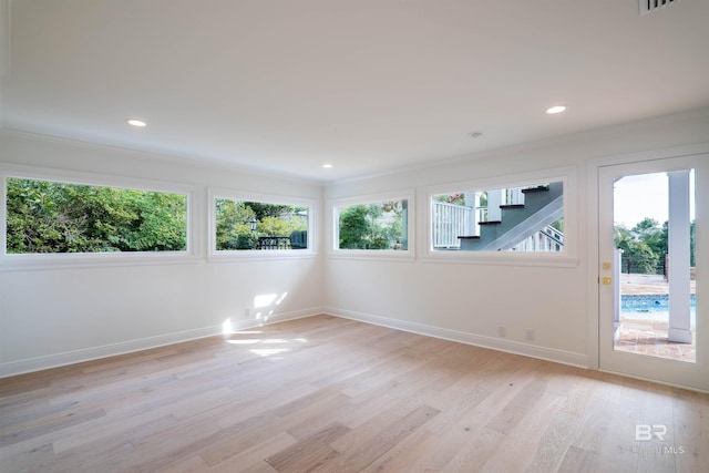 empty room with ornamental molding and light wood-type flooring