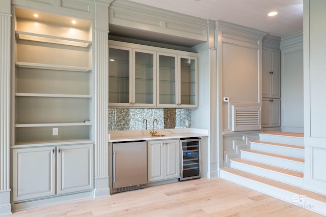 bar with sink, tasteful backsplash, wine cooler, fridge, and light wood-type flooring