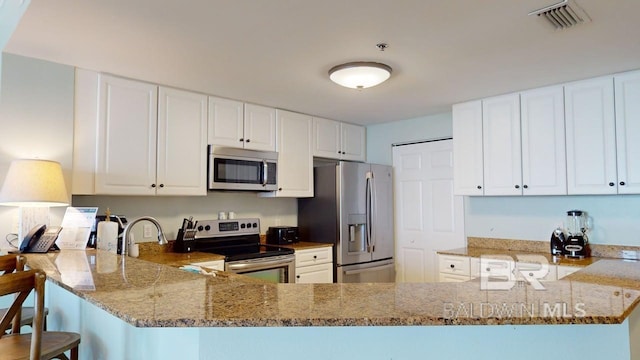 375 Beach Club Trl Unit A-1608, Gulf Shores, AL 36542 - kitchen with stainless steel appliances, light stone countertops, a peninsula, and white cabinetry