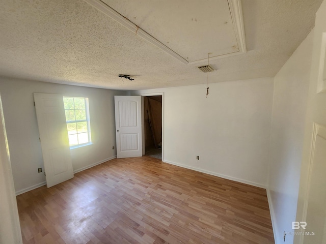 unfurnished room with a textured ceiling and light hardwood / wood-style flooring