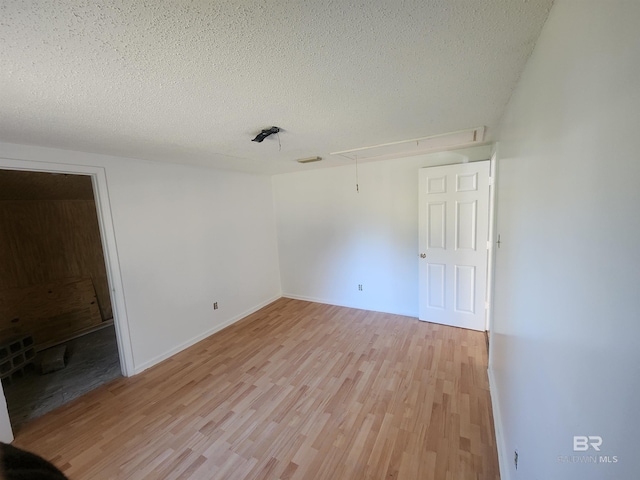 spare room featuring a textured ceiling and light hardwood / wood-style flooring