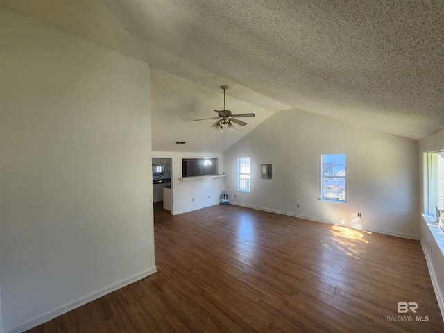 unfurnished living room featuring lofted ceiling, ceiling fan, dark wood-type flooring, and a textured ceiling