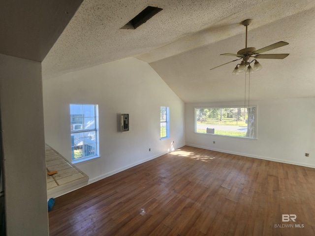 unfurnished living room with vaulted ceiling, ceiling fan, dark hardwood / wood-style flooring, and a textured ceiling