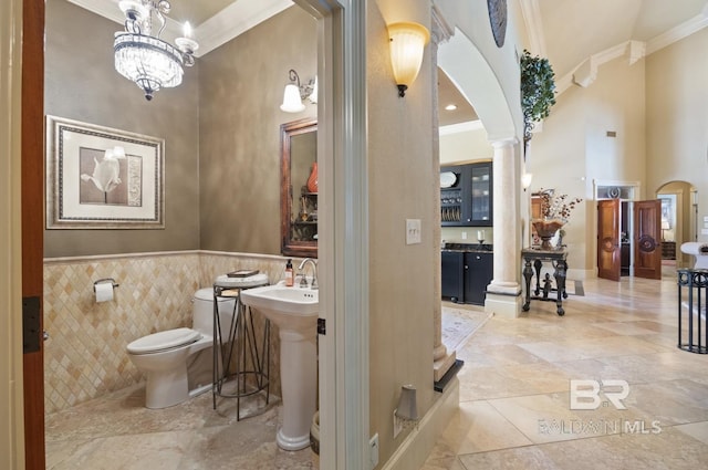 bathroom with decorative columns, ornamental molding, a high ceiling, and toilet