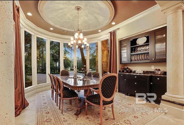 dining area featuring crown molding, a tray ceiling, a chandelier, and decorative columns