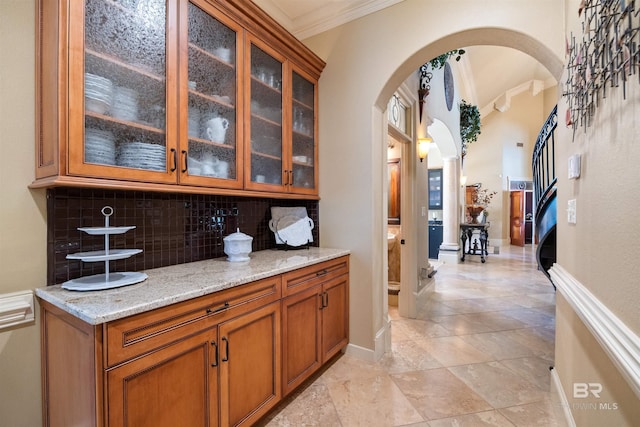 bar featuring crown molding, light stone countertops, and backsplash