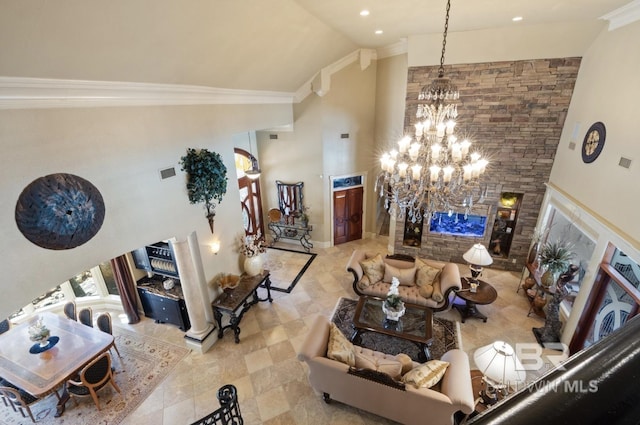 living room featuring an inviting chandelier, high vaulted ceiling, a stone fireplace, and ornamental molding