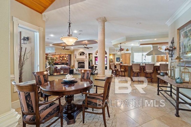 dining space with vaulted ceiling, light tile patterned floors, ornamental molding, ceiling fan, and decorative columns