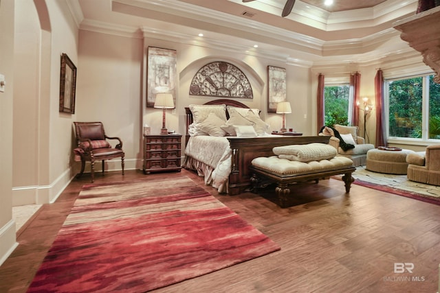 bedroom featuring crown molding, wood-type flooring, and a tray ceiling