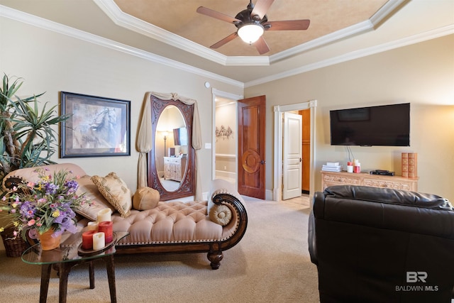 carpeted living room with a tray ceiling, ornamental molding, and ceiling fan