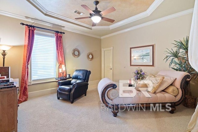 living room with ceiling fan, ornamental molding, a tray ceiling, and carpet