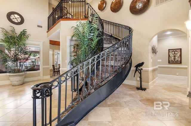 staircase featuring a high ceiling and ornamental molding