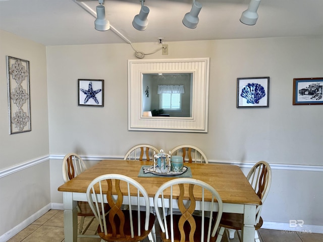 tiled dining space featuring track lighting