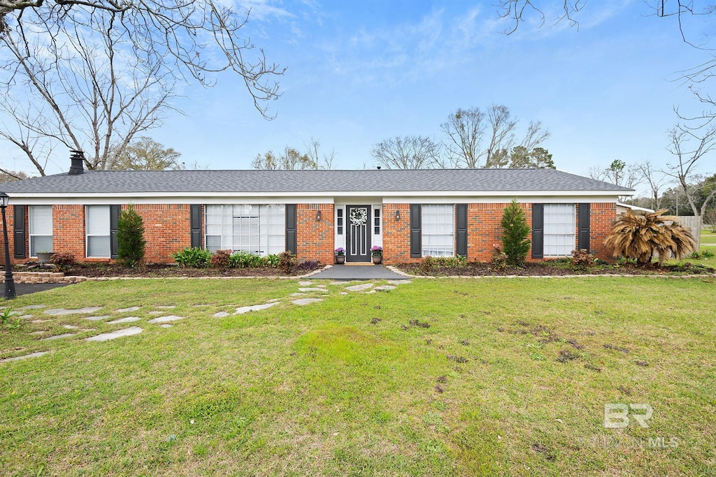 ranch-style house with a front yard, brick siding, and a chimney