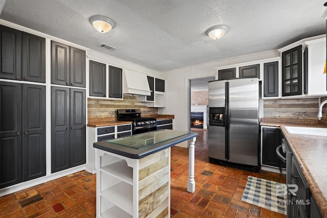 kitchen with visible vents, open shelves, premium range hood, stainless steel appliances, and a sink