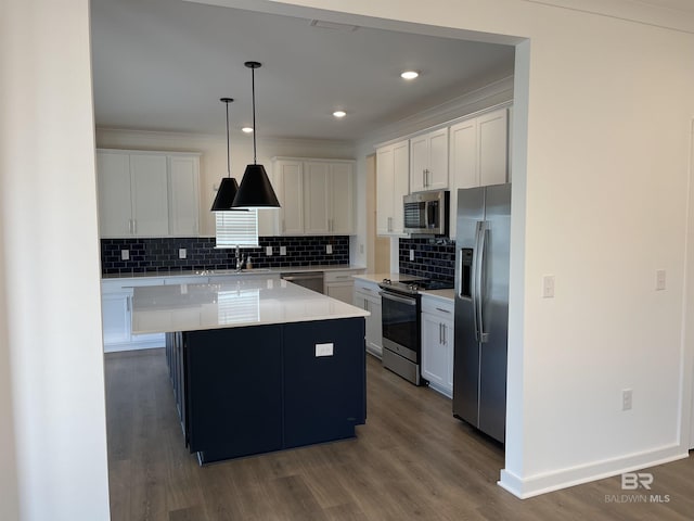 kitchen with pendant lighting, appliances with stainless steel finishes, white cabinetry, dark hardwood / wood-style floors, and a kitchen island