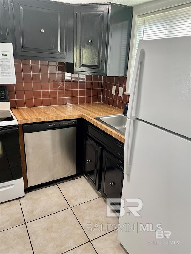 kitchen with tasteful backsplash, light tile patterned floors, and white appliances