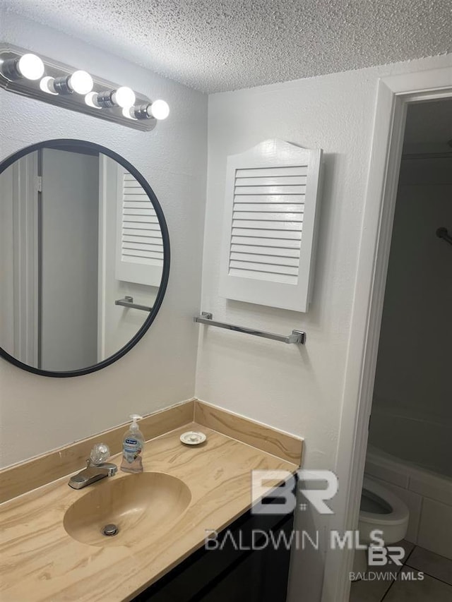 bathroom with tile patterned flooring, vanity, toilet, and a textured ceiling