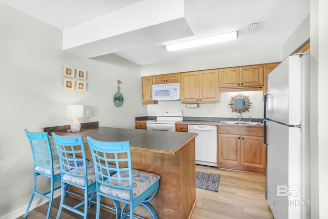 kitchen featuring a peninsula, white appliances, visible vents, light wood finished floors, and dark countertops