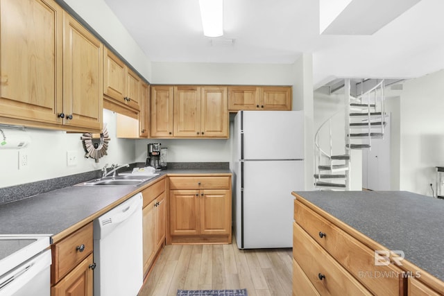 kitchen featuring light wood-style floors, dark countertops, white appliances, and a sink