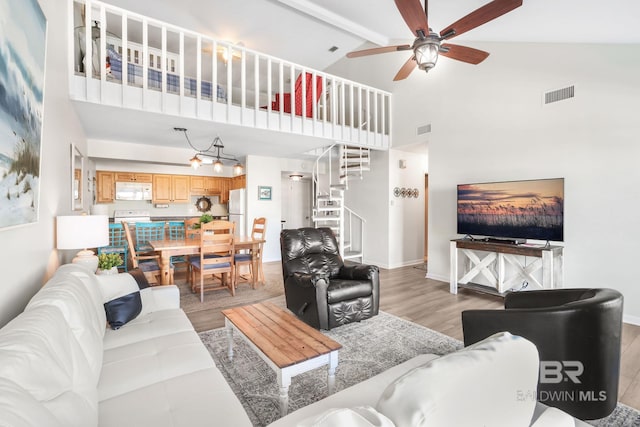 living room with light wood-style floors, visible vents, stairway, and baseboards