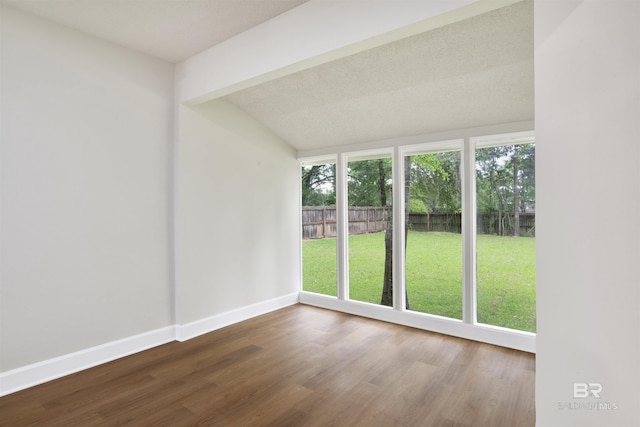 spare room with baseboards, wood finished floors, and vaulted ceiling