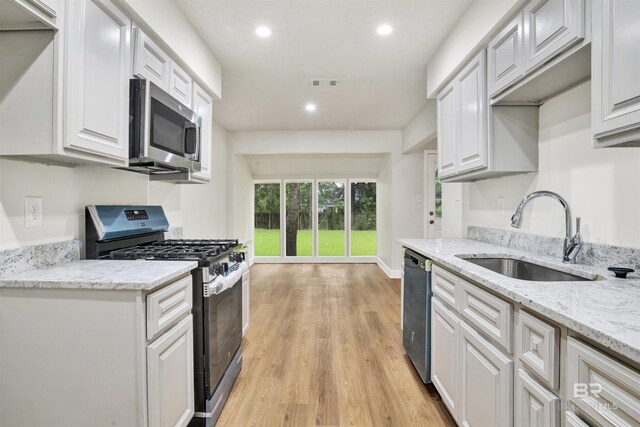 kitchen with stainless steel appliances, a sink, recessed lighting, light wood-style floors, and white cabinets