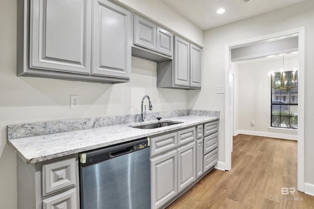 kitchen featuring dishwasher, a sink, light wood finished floors, gray cabinets, and baseboards