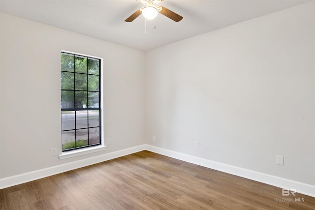 unfurnished room featuring wood finished floors, baseboards, and ceiling fan
