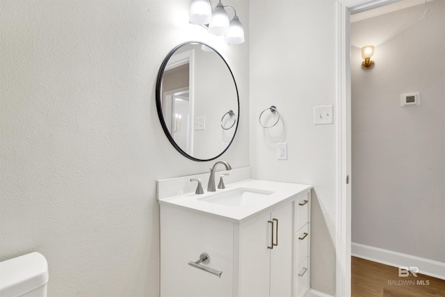 bathroom with vanity, toilet, baseboards, and wood finished floors