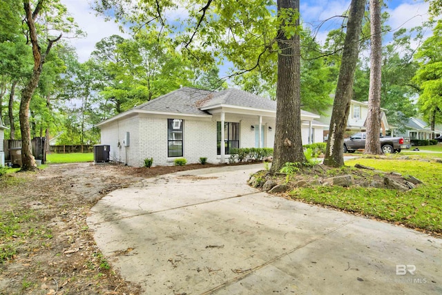 ranch-style house with cooling unit, brick siding, a porch, and roof with shingles