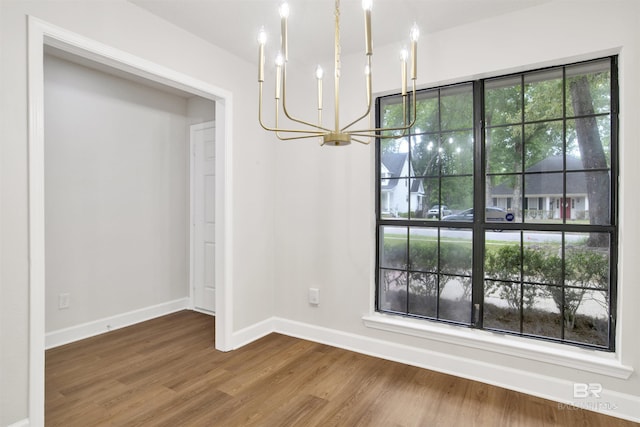 unfurnished dining area featuring a chandelier, wood finished floors, and baseboards