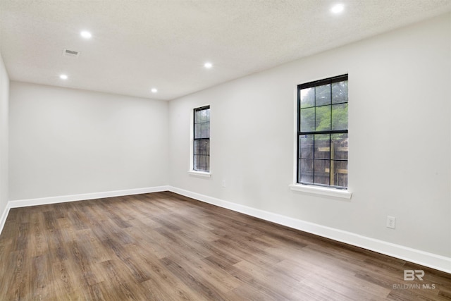 unfurnished room with recessed lighting, wood finished floors, and baseboards