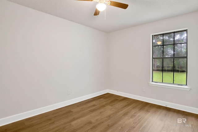 empty room featuring baseboards, wood finished floors, plenty of natural light, and ceiling fan