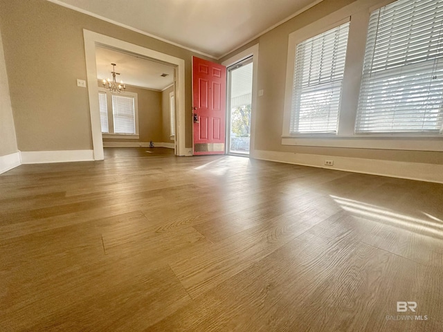 unfurnished living room featuring hardwood / wood-style floors, a notable chandelier, and crown molding